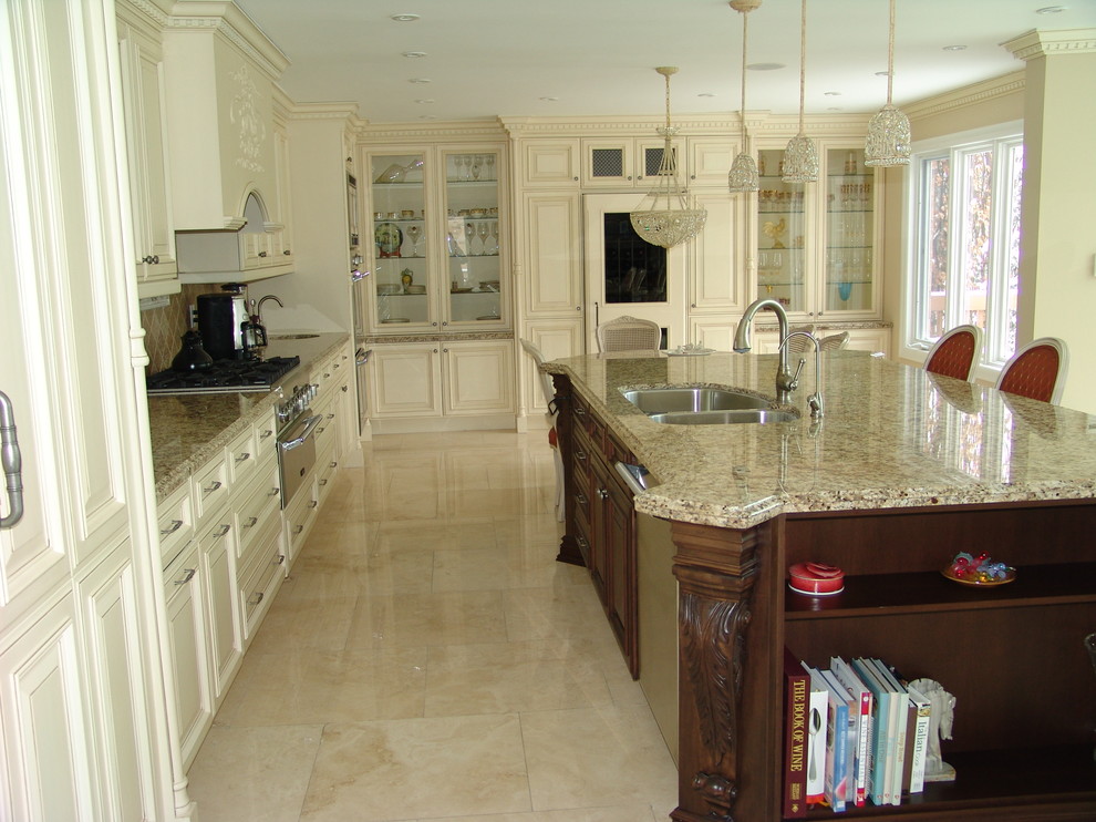 Inredning av ett klassiskt stort kök, med luckor med upphöjd panel, gula skåp, granitbänkskiva, beige stänkskydd, stänkskydd i stenkakel, rostfria vitvaror, marmorgolv, en köksö och en undermonterad diskho