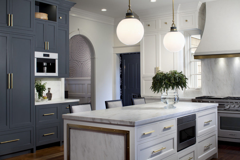 Inredning av ett klassiskt avskilt vit vitt kök, med skåp i shakerstil, blå skåp, vitt stänkskydd, stänkskydd i sten, rostfria vitvaror, mörkt trägolv, en köksö och brunt golv