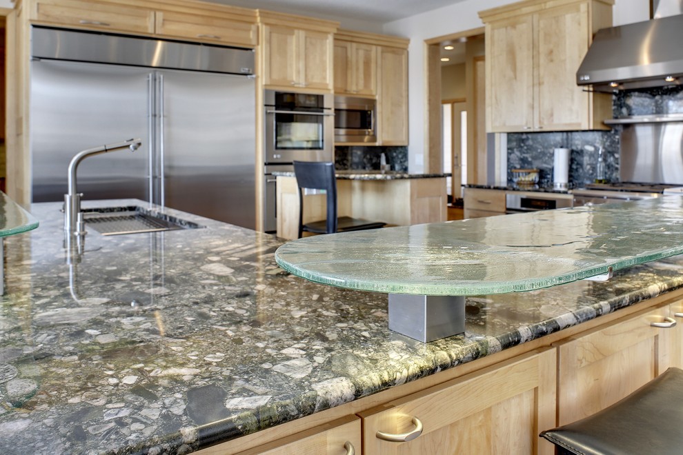 Exempel på ett mycket stort modernt kök, med en enkel diskho, skåp i shakerstil, skåp i ljust trä, granitbänkskiva, grönt stänkskydd, stänkskydd i sten, rostfria vitvaror, klinkergolv i porslin och flera köksöar