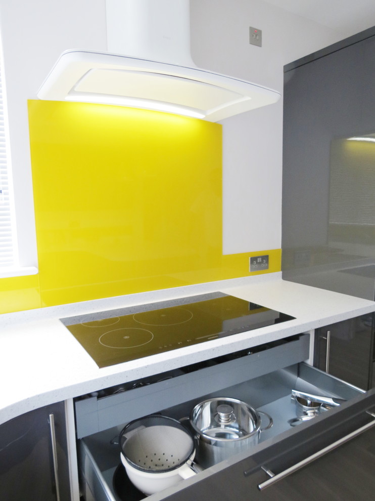 Foto på ett funkis kök, med en undermonterad diskho, grå skåp, bänkskiva i koppar, gult stänkskydd, glaspanel som stänkskydd, rostfria vitvaror och en halv köksö