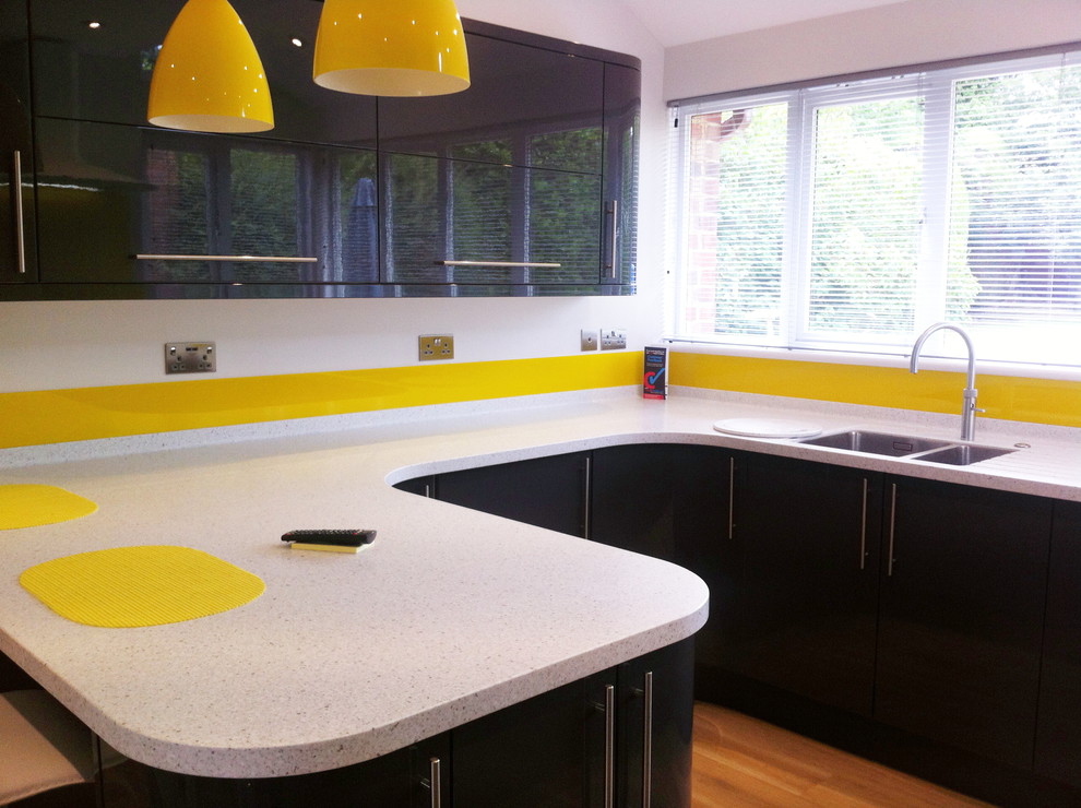 Modern inredning av ett kök, med en undermonterad diskho, grå skåp, bänkskiva i koppar, gult stänkskydd, glaspanel som stänkskydd, rostfria vitvaror och en halv köksö