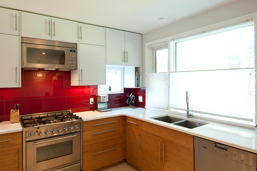 Moderne Wohnküche in U-Form mit Unterbauwaschbecken, flächenbündigen Schrankfronten, weißen Schränken, Quarzwerkstein-Arbeitsplatte, Küchenrückwand in Rot, Rückwand aus Glasfliesen und Küchengeräten aus Edelstahl in Ottawa
