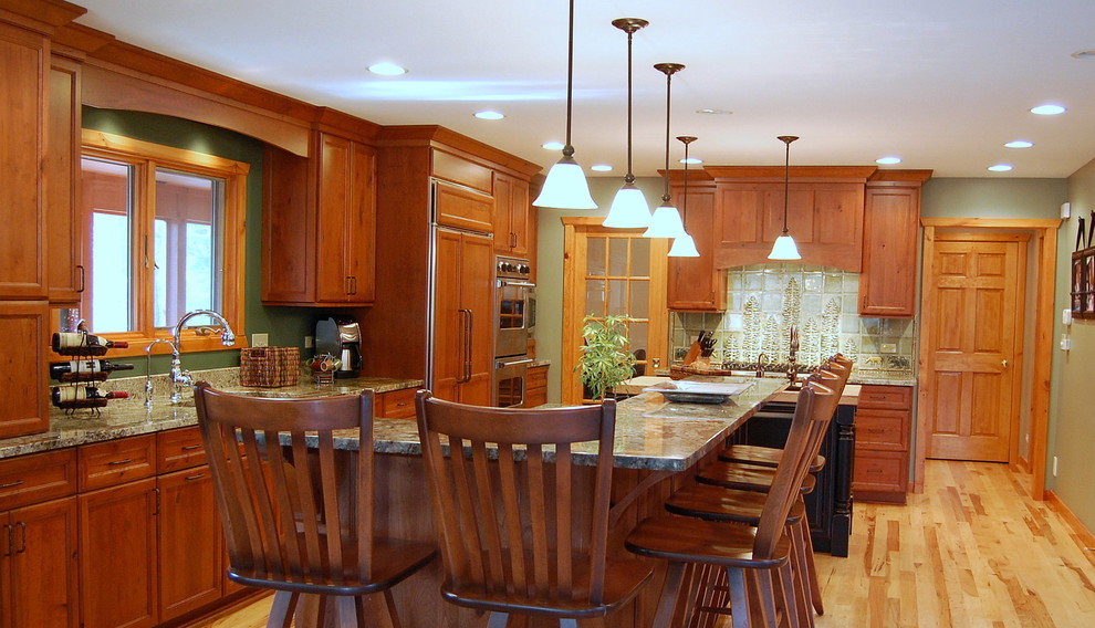 Inredning av ett rustikt mellanstort linjärt kök och matrum, med en undermonterad diskho, släta luckor, skåp i mellenmörkt trä, granitbänkskiva, rostfria vitvaror, grönt stänkskydd, stänkskydd i keramik, ljust trägolv, flera köksöar och brunt golv