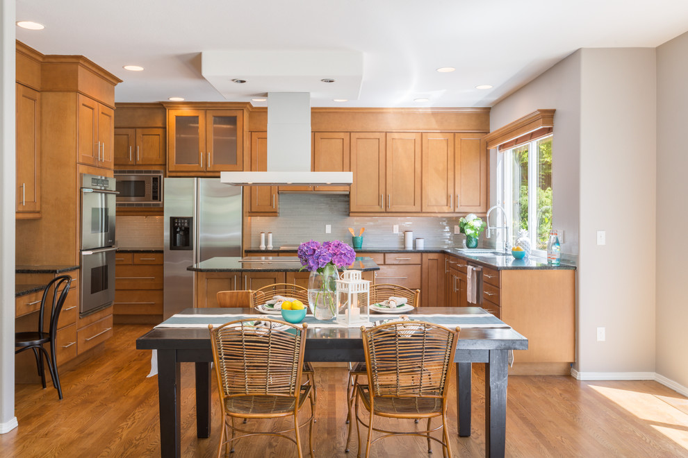 This is an example of a classic u-shaped open plan kitchen in Seattle with shaker cabinets, medium wood cabinets, grey splashback, matchstick tiled splashback, stainless steel appliances, medium hardwood flooring, an island and brown floors.