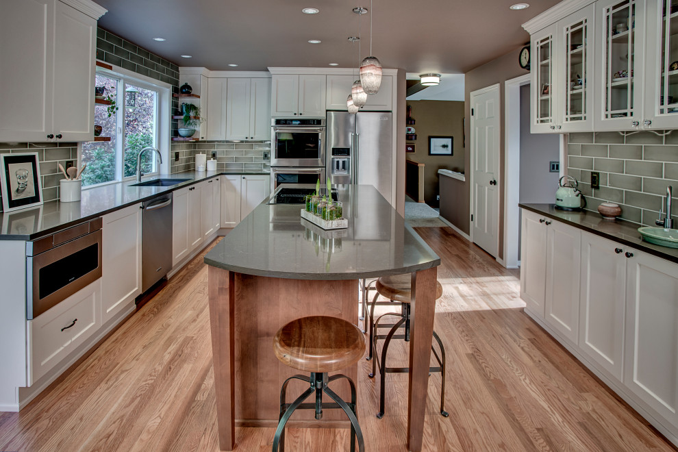 Inspiration for a mid-sized transitional medium tone wood floor and red floor kitchen remodel in Seattle with an undermount sink, recessed-panel cabinets, white cabinets, quartz countertops, green backsplash, ceramic backsplash, stainless steel appliances, an island and brown countertops
