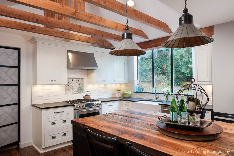 Example of a mountain style u-shaped medium tone wood floor open concept kitchen design in Seattle with shaker cabinets, white cabinets, granite countertops, white backsplash, ceramic backsplash, stainless steel appliances, an island and a farmhouse sink