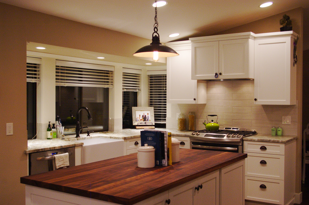 Foto på ett mellanstort lantligt kök, med en rustik diskho, skåp i shakerstil, vita skåp, granitbänkskiva, rostfria vitvaror, mellanmörkt trägolv, beige stänkskydd, stänkskydd i stenkakel och en köksö