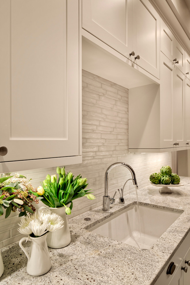Photo of an expansive contemporary kitchen pantry in Seattle with a submerged sink, shaker cabinets, white cabinets, granite worktops, white splashback, glass tiled splashback and an island.