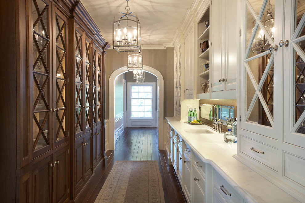 Cette image montre une cuisine bicolore traditionnelle avec un placard à porte vitrée, des portes de placard blanches et plan de travail en marbre.