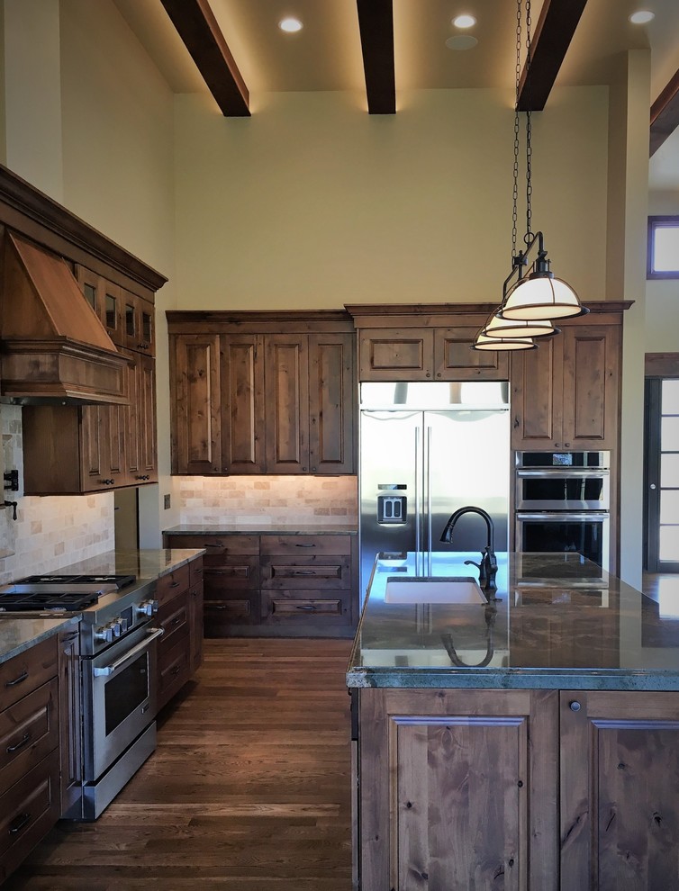Exempel på ett stort rustikt l-kök, med en undermonterad diskho, luckor med upphöjd panel, bruna skåp, granitbänkskiva, beige stänkskydd, stänkskydd i terrakottakakel, rostfria vitvaror, mellanmörkt trägolv och en köksö