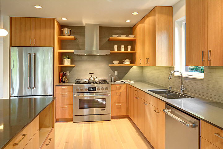 Bild på ett mellanstort funkis kök, med en undermonterad diskho, släta luckor, skåp i mellenmörkt trä, grönt stänkskydd, stänkskydd i stenkakel, rostfria vitvaror, ljust trägolv, en halv köksö, bänkskiva i kvarts och beiget golv