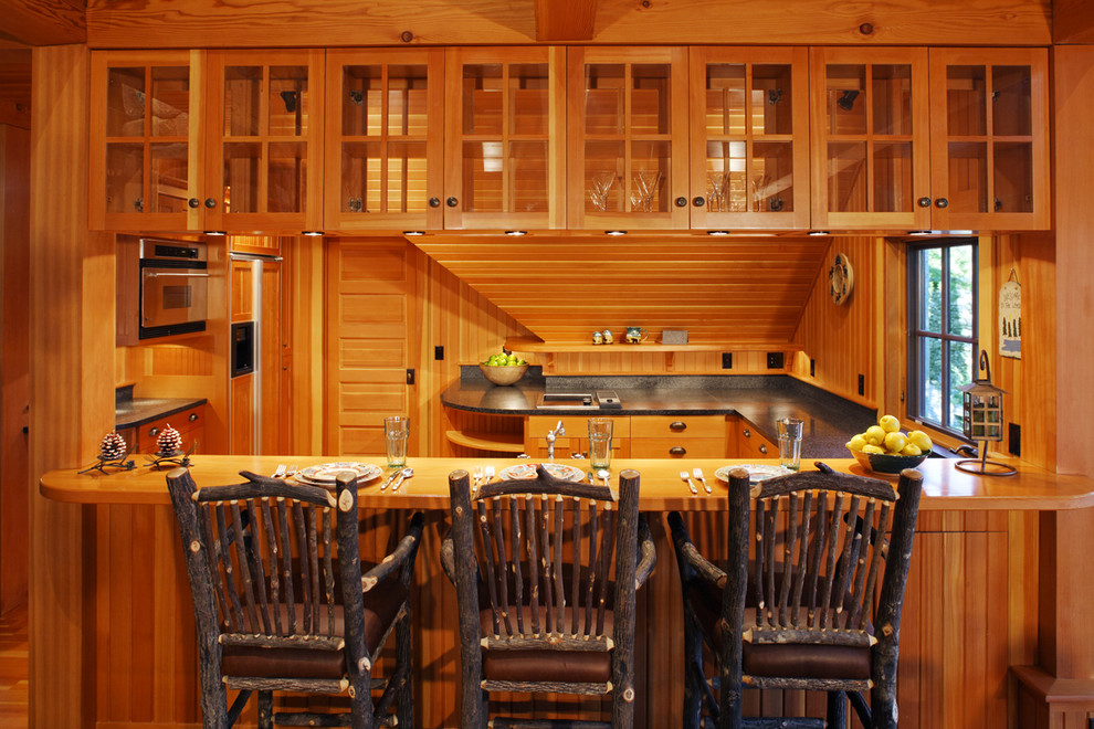 Aménagement d'une cuisine montagne en bois brun avec un placard à porte vitrée.