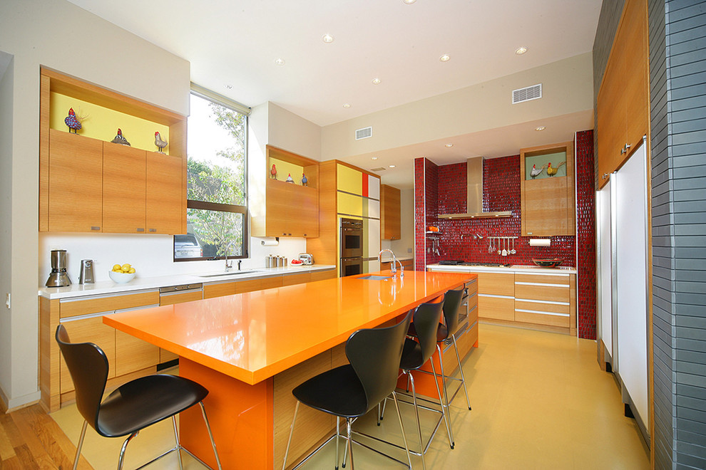 На фото: кухня в современном стиле с техникой из нержавеющей стали, оранжевой столешницей и барной стойкой