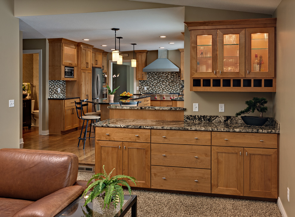 Bild på ett mellanstort amerikanskt svart svart kök, med en undermonterad diskho, luckor med infälld panel, skåp i mellenmörkt trä, granitbänkskiva, flerfärgad stänkskydd, stänkskydd i stickkakel, rostfria vitvaror, mellanmörkt trägolv, en köksö och brunt golv