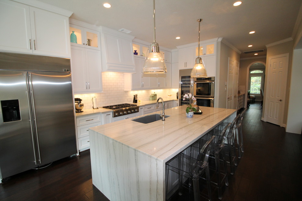 Example of a large transitional l-shaped dark wood floor eat-in kitchen design in Houston with white cabinets, white backsplash, stainless steel appliances, an island, a double-bowl sink, shaker cabinets, marble countertops and subway tile backsplash
