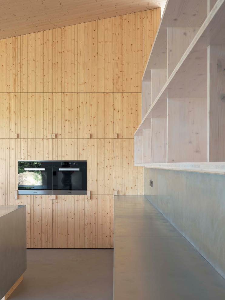 Cette image montre une grande cuisine ouverte design en bois clair avec un placard à porte plane, un plan de travail en zinc, une crédence grise, îlot et un plan de travail gris.