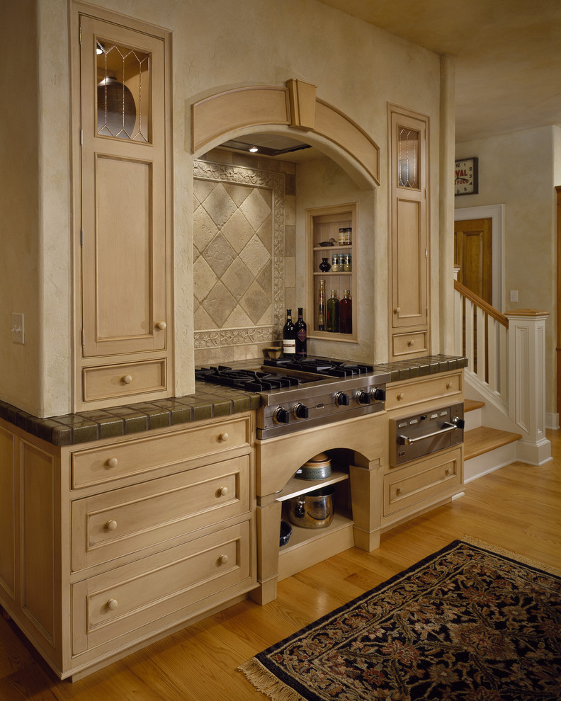 ニューヨークにあるトラディショナルスタイルのおしゃれなキッチン (インセット扉のキャビネット、淡色木目調キャビネット、ベージュキッチンパネル、石タイルのキッチンパネル、シルバーの調理設備、タイルカウンター) の写真