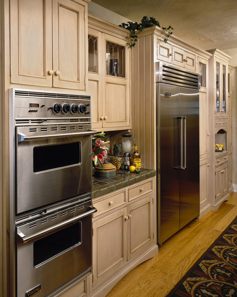 Diseño de cocina tradicional con puertas de armario de madera clara y electrodomésticos de acero inoxidable