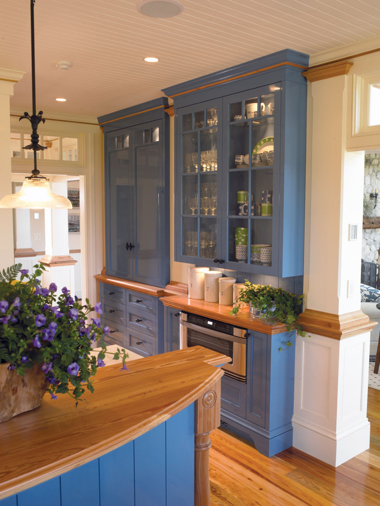 На фото: кухня в классическом стиле с стеклянными фасадами, деревянной столешницей и синими фасадами