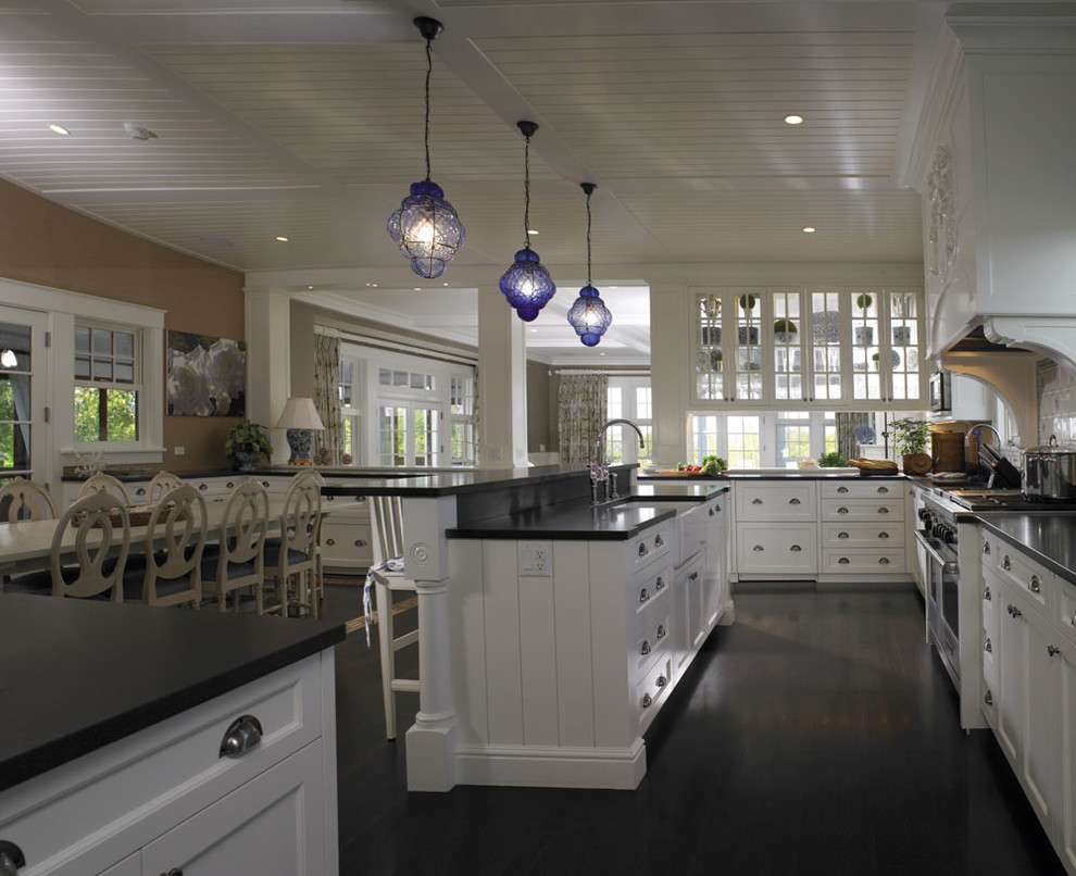 Kitchen - large traditional dark wood floor kitchen idea in Boston with a farmhouse sink, recessed-panel cabinets, white cabinets, granite countertops, white backsplash, ceramic backsplash, paneled appliances and an island