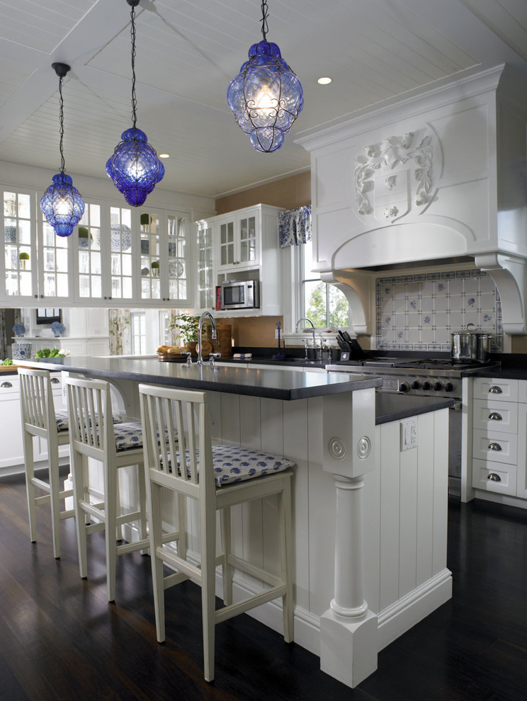 Klassisk inredning av ett stort kök, med vita skåp, en rustik diskho, luckor med infälld panel, granitbänkskiva, vitt stänkskydd, stänkskydd i keramik, integrerade vitvaror, mörkt trägolv och en köksö