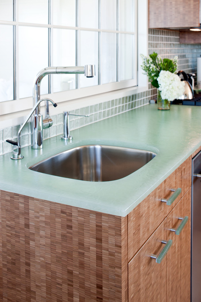 Small beach style l-shaped light wood floor eat-in kitchen photo in Boston with an undermount sink, flat-panel cabinets, light wood cabinets, glass countertops, green backsplash, stainless steel appliances, no island, glass tile backsplash and turquoise countertops