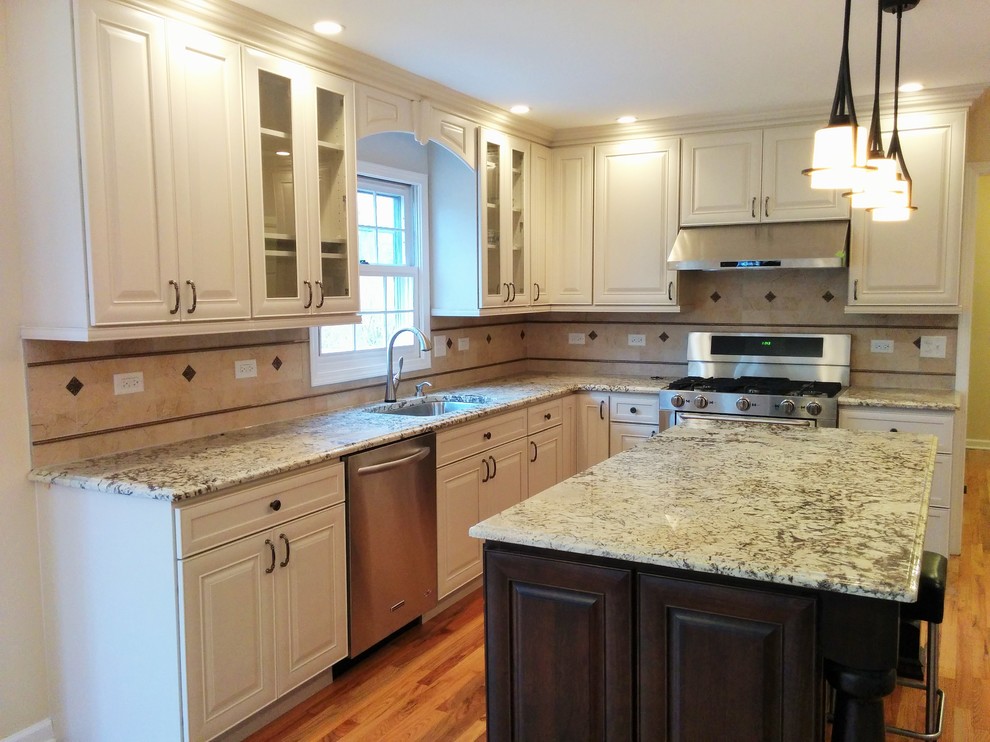 Exempel på ett mellanstort klassiskt kök, med en enkel diskho, luckor med upphöjd panel, svarta skåp, granitbänkskiva, beige stänkskydd, stänkskydd i sten, rostfria vitvaror, mellanmörkt trägolv och en köksö
