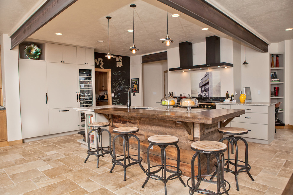 Inspiration for a large industrial l-shaped travertine floor and beige floor kitchen remodel in Denver with an undermount sink, flat-panel cabinets, beige cabinets, granite countertops, paneled appliances, an island and multicolored countertops