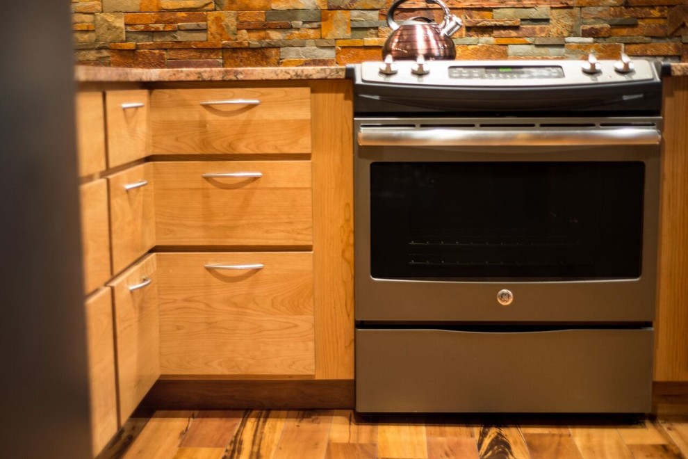 Amerikansk inredning av ett avskilt, mellanstort l-kök, med en undermonterad diskho, släta luckor, skåp i ljust trä, granitbänkskiva, flerfärgad stänkskydd, stänkskydd i stenkakel, rostfria vitvaror, ljust trägolv och en köksö