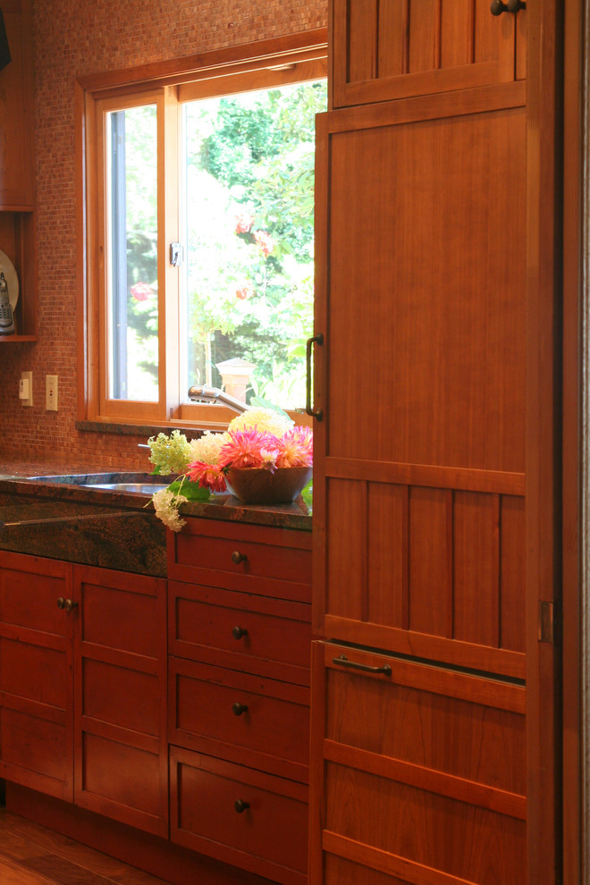 Exempel på ett avskilt klassiskt kök, med en undermonterad diskho, luckor med infälld panel, skåp i mellenmörkt trä, granitbänkskiva, flerfärgad stänkskydd, stänkskydd i mosaik och integrerade vitvaror