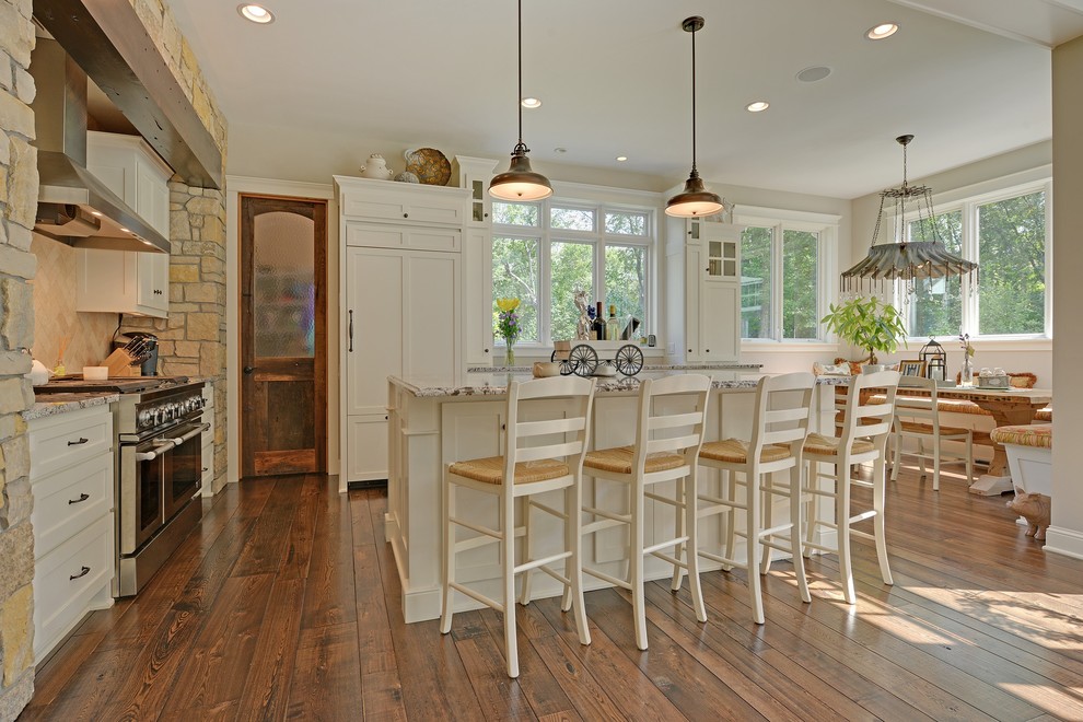 На фото: кухня в классическом стиле с обеденным столом, белыми фасадами, бежевым фартуком и техникой под мебельный фасад