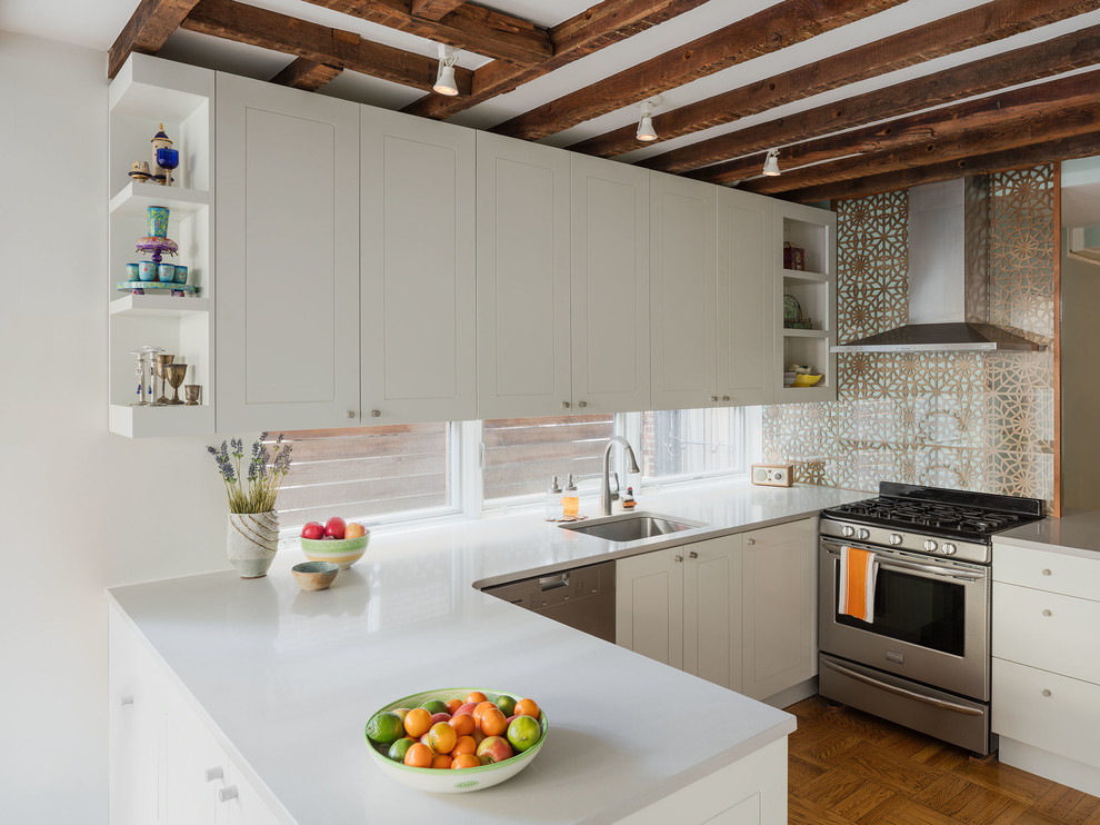 Foto på ett litet funkis vit kök och matrum, med släta luckor, vita skåp, bänkskiva i kvarts, fönster som stänkskydd, rostfria vitvaror, mellanmörkt trägolv, en halv köksö och brunt golv