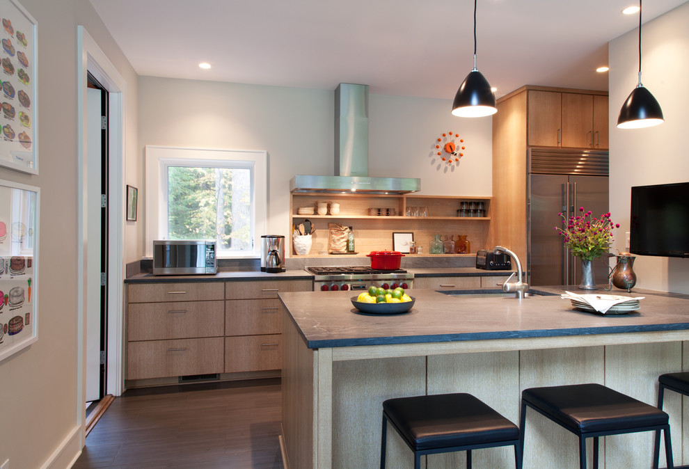 Cette image montre une cuisine parallèle design en bois clair avec un évier encastré, un placard à porte plane et un électroménager en acier inoxydable.