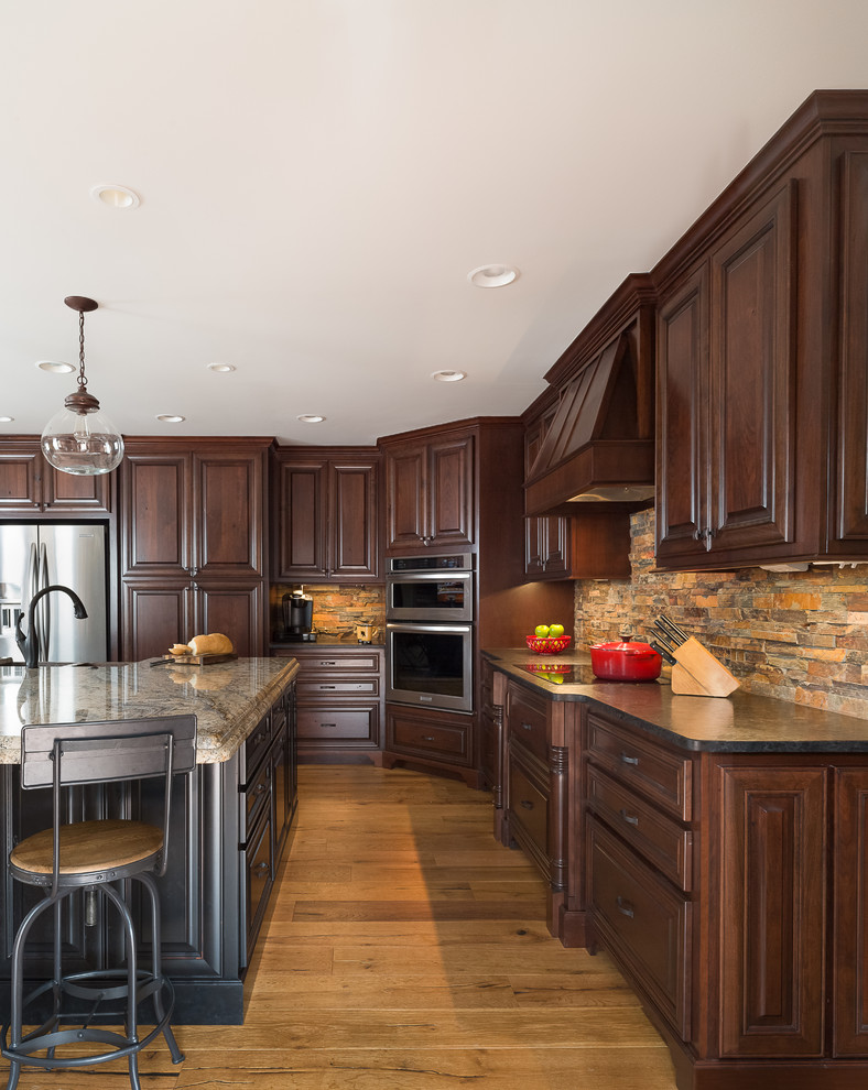 Example of a large mountain style u-shaped porcelain tile eat-in kitchen design in Atlanta with a farmhouse sink, raised-panel cabinets, dark wood cabinets, granite countertops, multicolored backsplash, stone tile backsplash, stainless steel appliances and an island