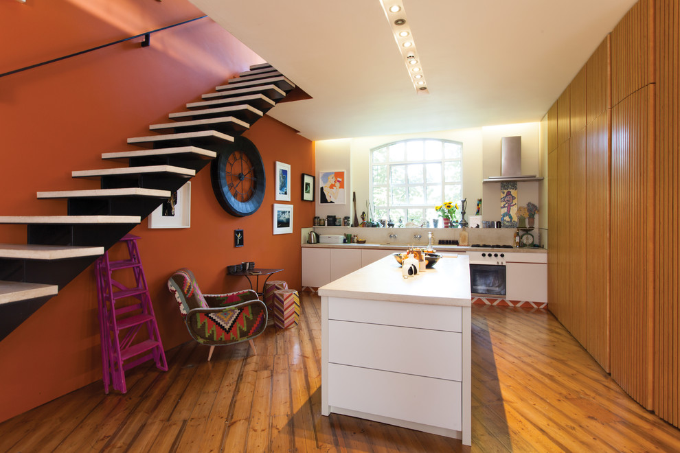 Bild på ett avskilt, mellanstort eklektiskt linjärt kök, med en nedsänkt diskho, släta luckor, vita skåp, marmorbänkskiva, stänkskydd i stenkakel, rostfria vitvaror, mellanmörkt trägolv och en köksö