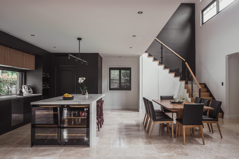 Foto på ett mellanstort funkis vit kök, med svarta skåp, bänkskiva i kvarts, travertin golv, en köksö, släta luckor, fönster som stänkskydd, rostfria vitvaror och beiget golv