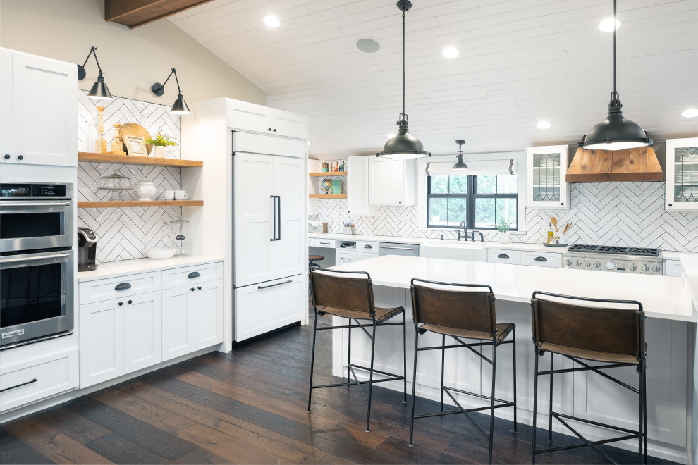 Inredning av ett lantligt vit vitt kök och matrum, med luckor med upphöjd panel, vita skåp, vitt stänkskydd, stänkskydd i keramik, en köksö och brunt golv