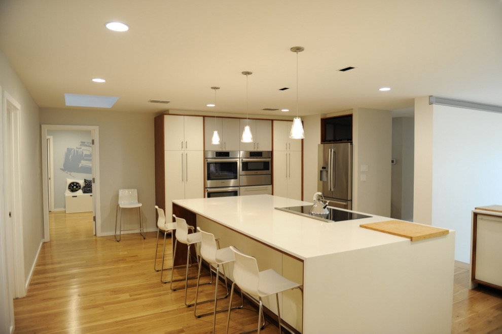 ダラスにある広いモダンスタイルのおしゃれなキッチン (フラットパネル扉のキャビネット、白いキャビネット、白いキッチンカウンター、白いキッチンパネル、磁器タイルのキッチンパネル、シルバーの調理設備、淡色無垢フローリング、ベージュの床) の写真