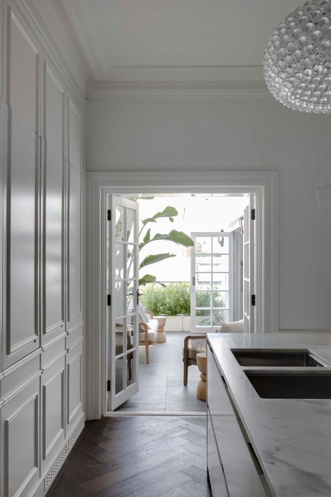Exempel på ett avskilt, litet klassiskt vit vitt parallellkök, med en undermonterad diskho, luckor med upphöjd panel, vita skåp, marmorbänkskiva, mörkt trägolv och en köksö