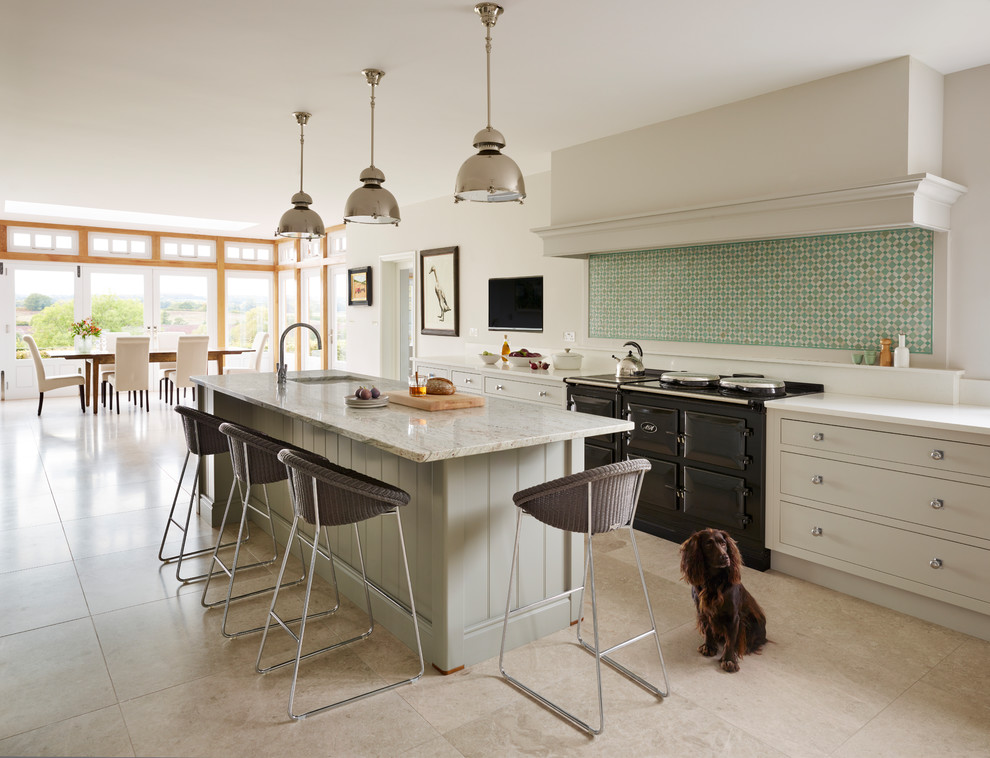 Photo of a classic kitchen/diner in London with a submerged sink, flat-panel cabinets, grey cabinets, green splashback, black appliances, an island and beige floors.