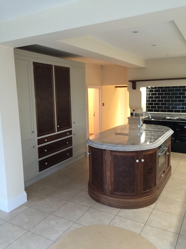 This is an example of a medium sized traditional l-shaped kitchen/diner in Other with a submerged sink, recessed-panel cabinets, granite worktops, integrated appliances and an island.