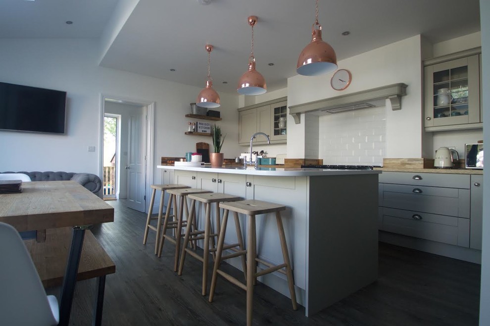 Bild på ett lantligt kök med öppen planlösning, med en rustik diskho, bänkskiva i kvartsit, vitt stänkskydd, stänkskydd i porslinskakel, rostfria vitvaror och en köksö