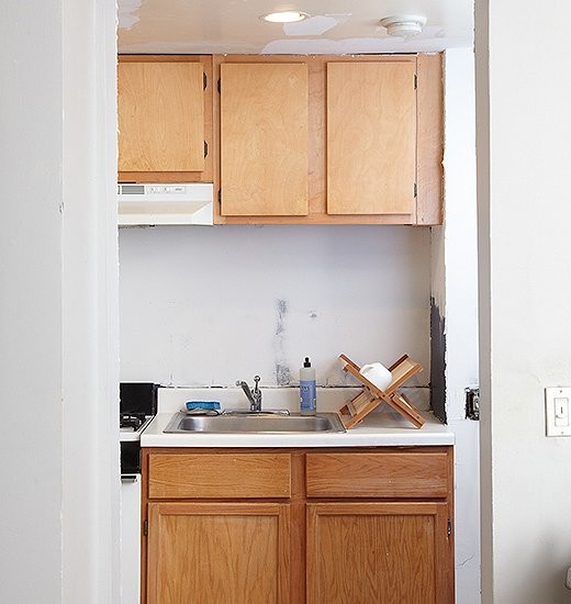 Idéer för ett avskilt, litet amerikanskt linjärt kök, med en nedsänkt diskho, skåp i shakerstil, blå skåp, laminatbänkskiva, stänkskydd med metallisk yta, spegel som stänkskydd, vita vitvaror och korkgolv