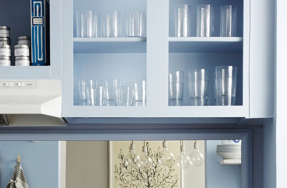 Bild på ett avskilt, litet amerikanskt linjärt kök, med en nedsänkt diskho, skåp i shakerstil, blå skåp, laminatbänkskiva, stänkskydd med metallisk yta, spegel som stänkskydd, vita vitvaror och korkgolv