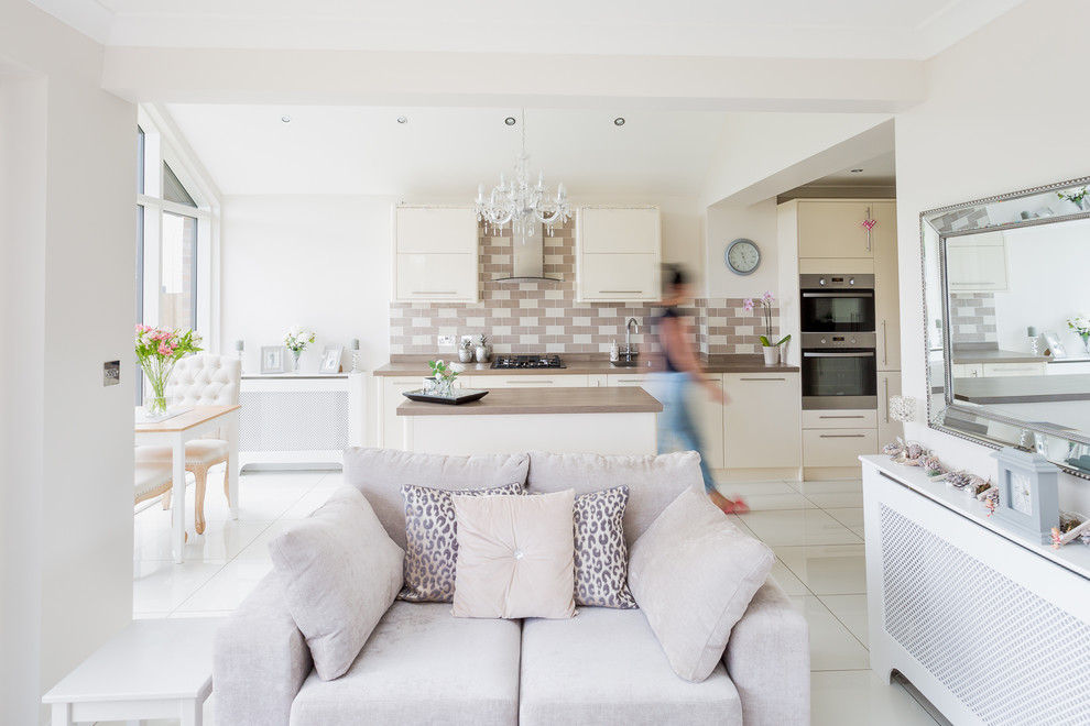 Medium sized contemporary l-shaped open plan kitchen in Glasgow with a built-in sink, flat-panel cabinets, beige cabinets, laminate countertops, beige splashback, ceramic splashback, stainless steel appliances, porcelain flooring, an island and white floors.