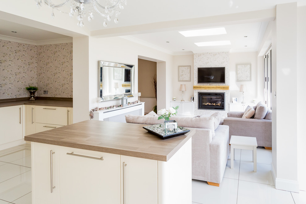 Medium sized contemporary l-shaped open plan kitchen in Glasgow with a built-in sink, flat-panel cabinets, beige cabinets, laminate countertops, beige splashback, ceramic splashback, stainless steel appliances, porcelain flooring, an island and white floors.