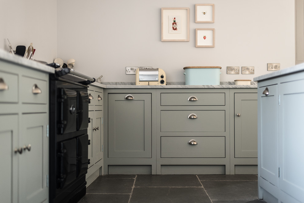 Inspiration for a mid-sized cottage slate floor kitchen remodel in Gloucestershire with a farmhouse sink, shaker cabinets, light wood cabinets, marble countertops and an island