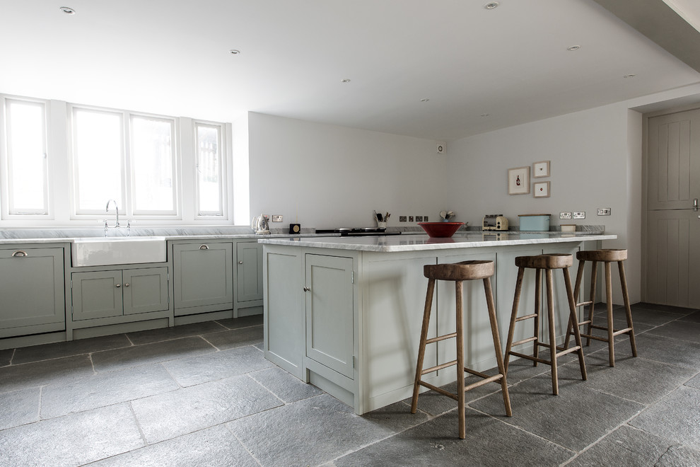 Example of a mid-sized country slate floor kitchen design in Gloucestershire with a farmhouse sink, shaker cabinets, light wood cabinets, marble countertops and an island
