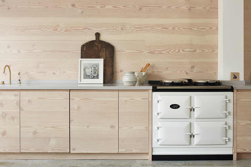 Foto de cocina escandinava grande abierta con fregadero integrado, armarios con paneles lisos, puertas de armario de madera clara, encimera de acrílico, suelo de cemento y una isla