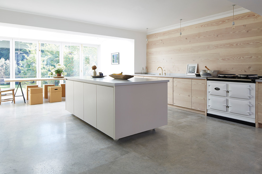Large scandinavian open plan kitchen in London with an integrated sink, flat-panel cabinets, light wood cabinets, composite countertops, concrete flooring and an island.